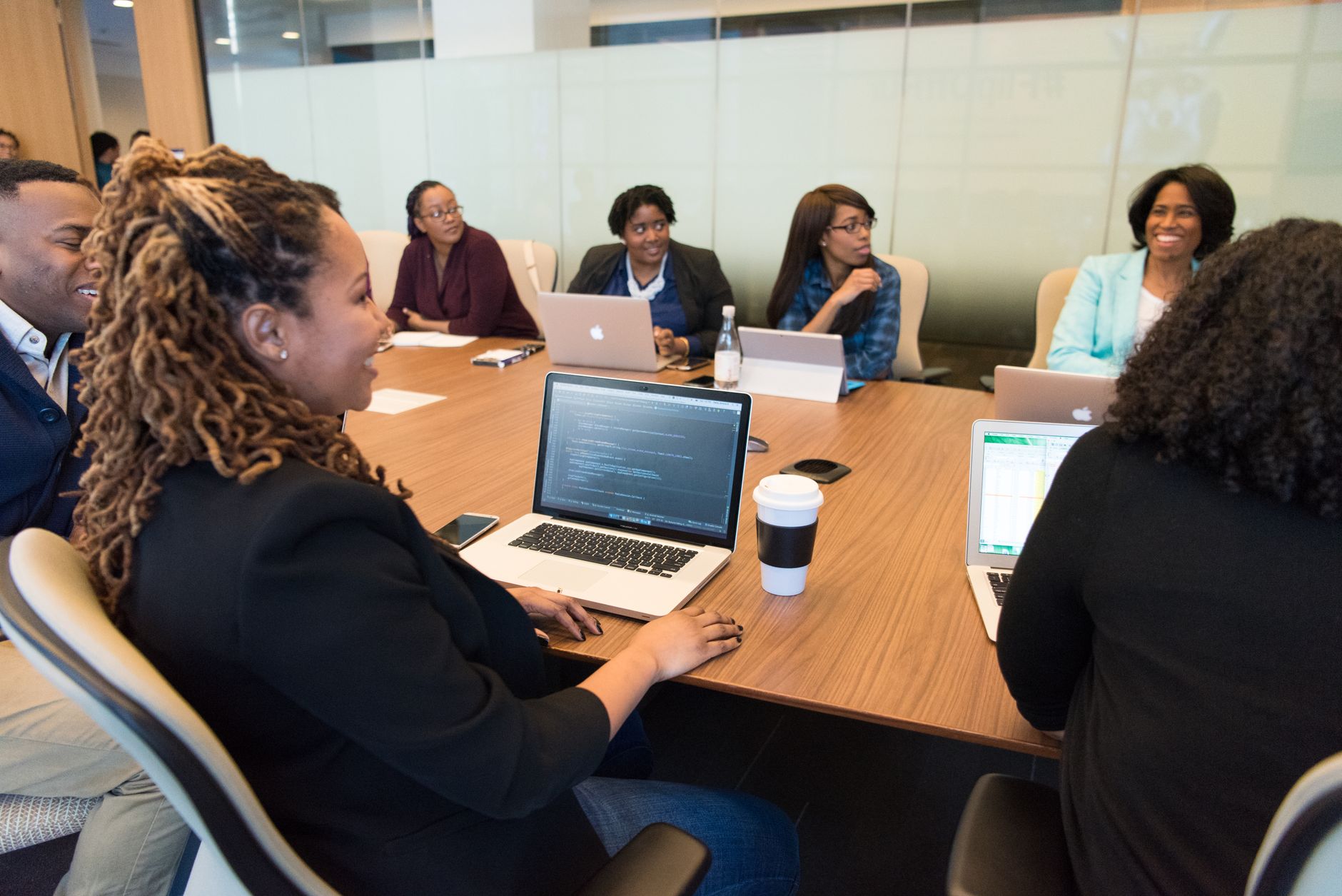 Small group seated around a meeting table with laptops